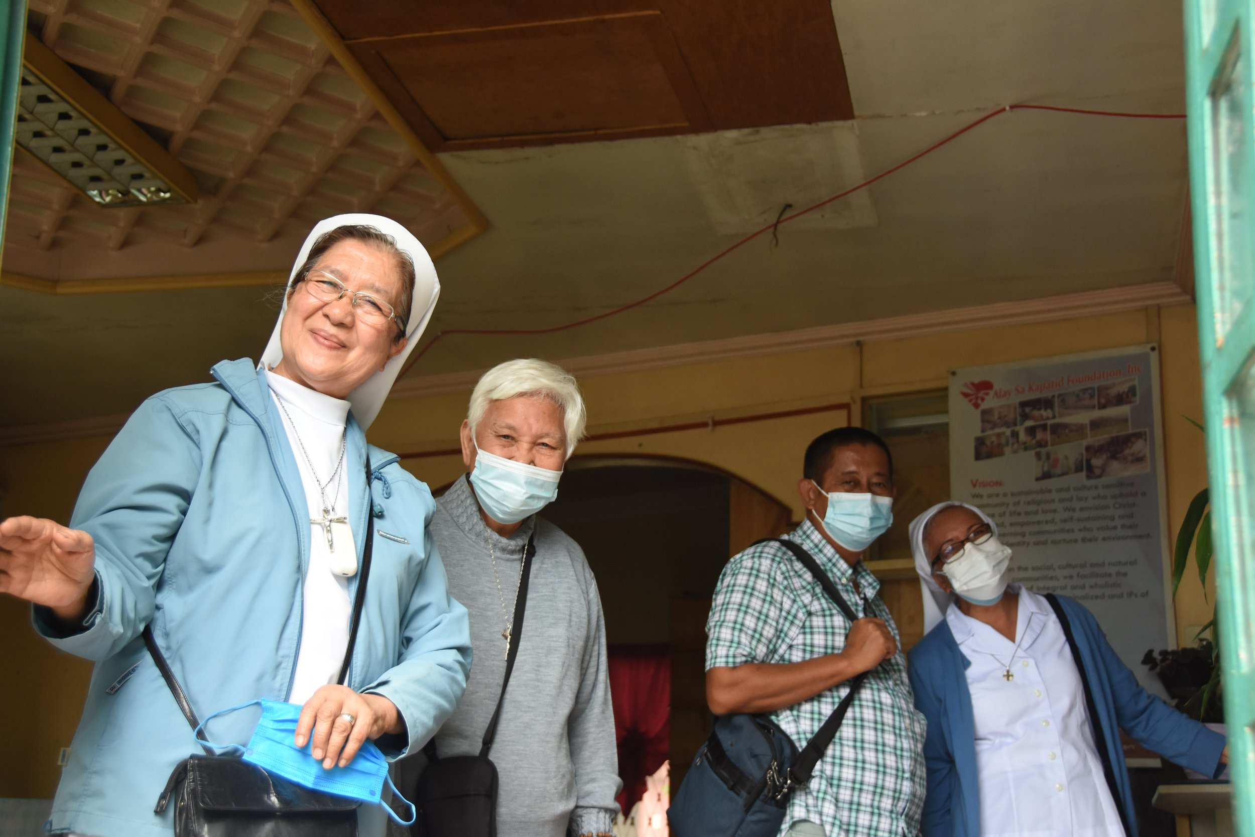 Local faith leaders waving to camera during water access site visits near Baguio City, Philippines